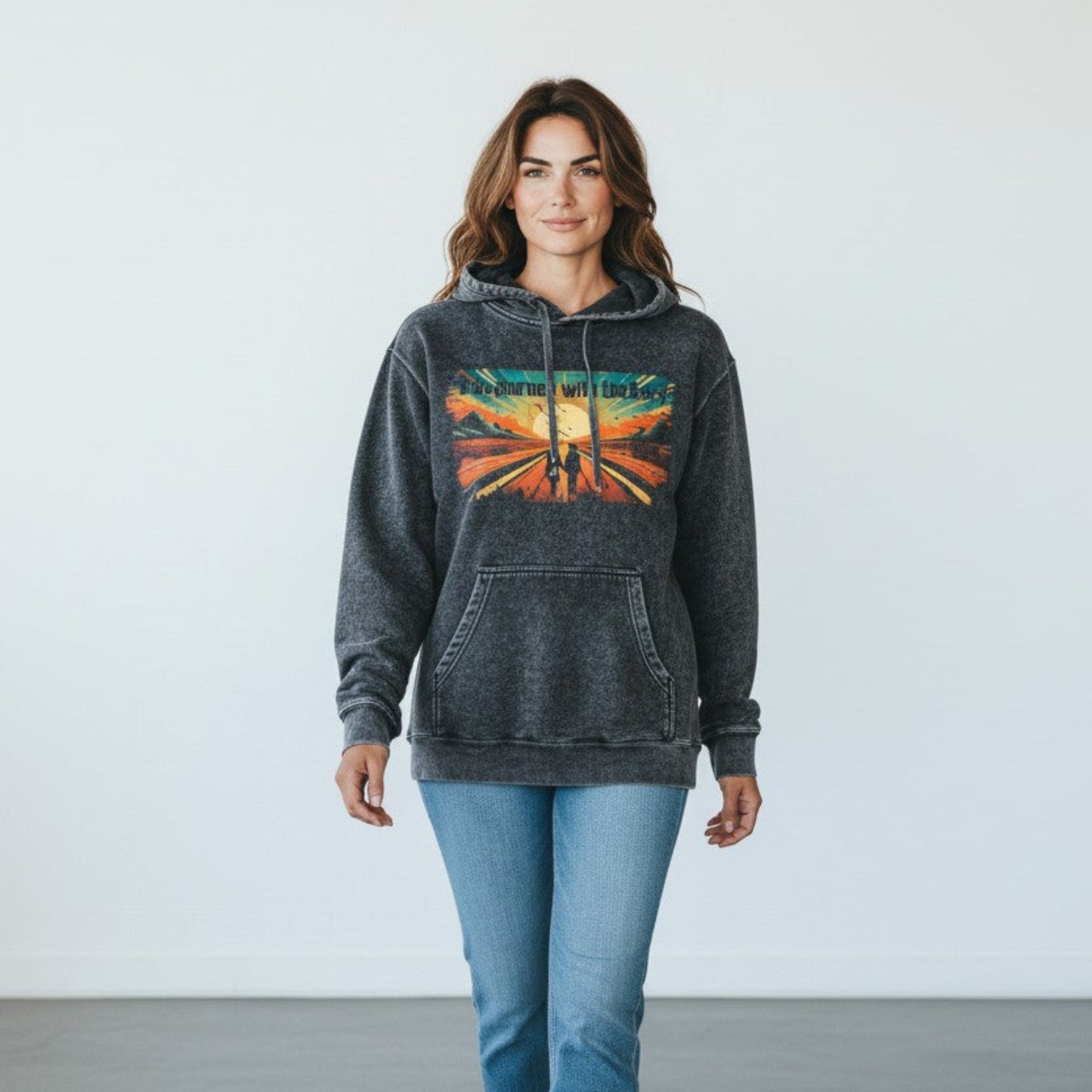 Woman wearing a dark gray vintage washed hoodie with a colorful graphic design on a plain background