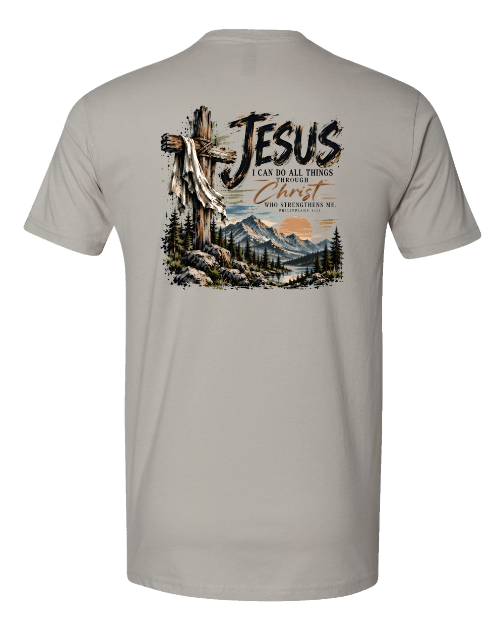 A gray crewneck t-shirt shown from the back, featuring a large graphic print of a wooden cross with a draped white cloth, mountains, pine trees, and the text 'JESUS I CAN DO ALL THINGS THROUGH Christ WHO STRENGTHENS ME'.