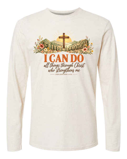 An off-white long-sleeve t-shirt with a graphic print on the chest. The graphic features a cross on a mountain with a rising sun, surrounded by flowers, and the text 'I CAN DO all things through Christ who Strengthens me PHILIPPIANS 4:13'.